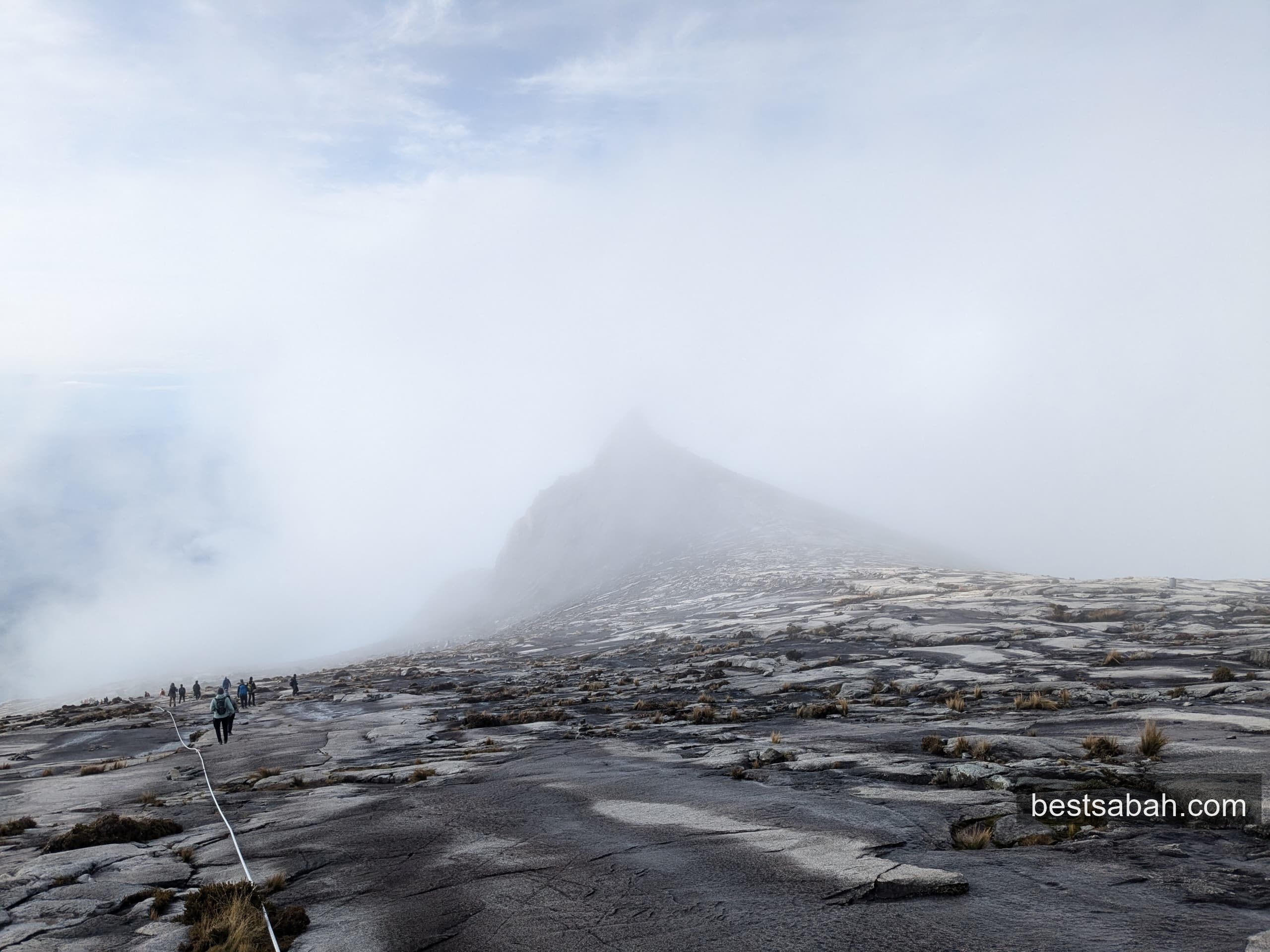 Hikers crossing the summit plateau of Mount Kinabalu in early morning mist