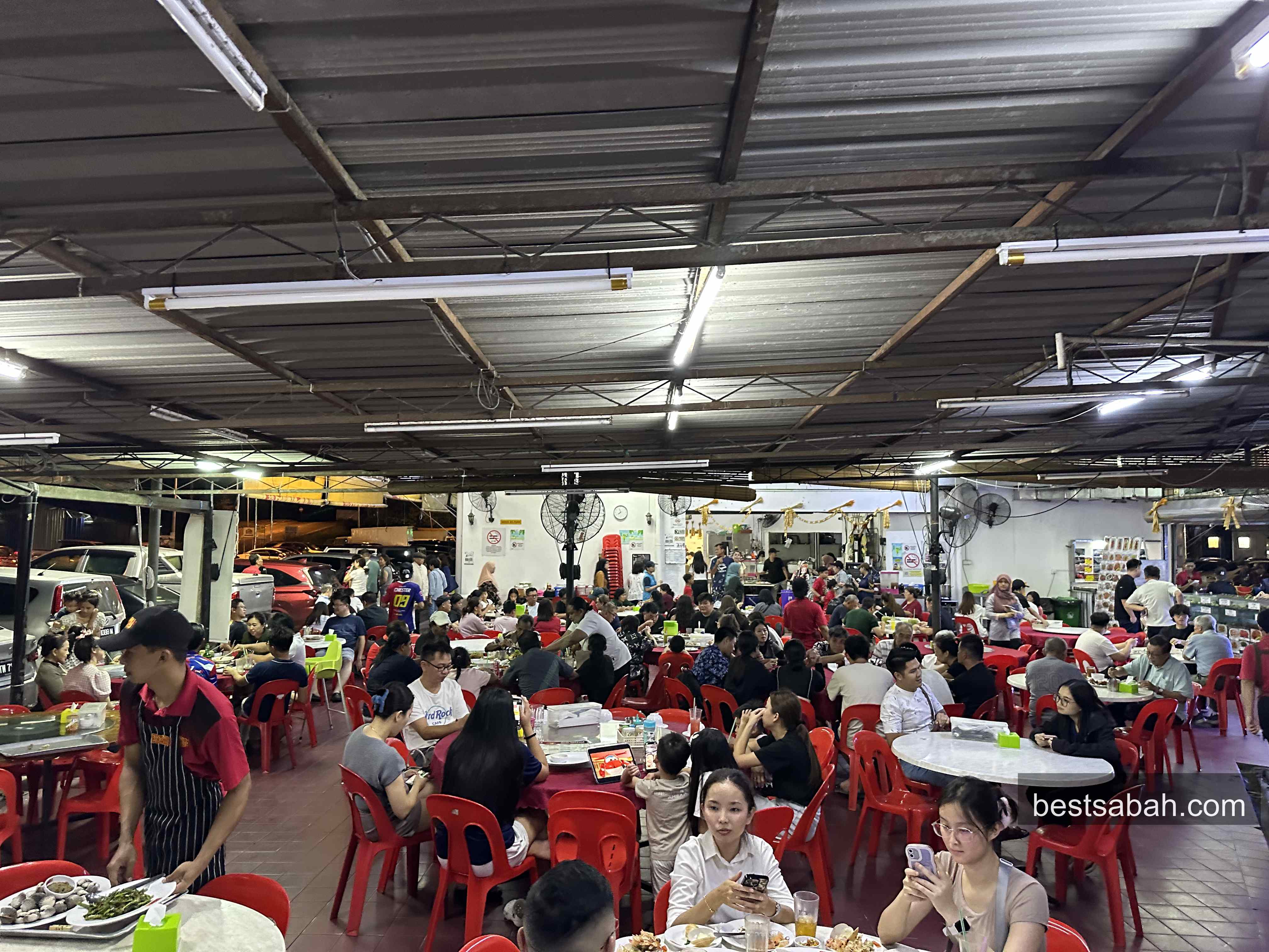 Interior of Sasa Seafood Restaurant packed with diners on red plastic chairs