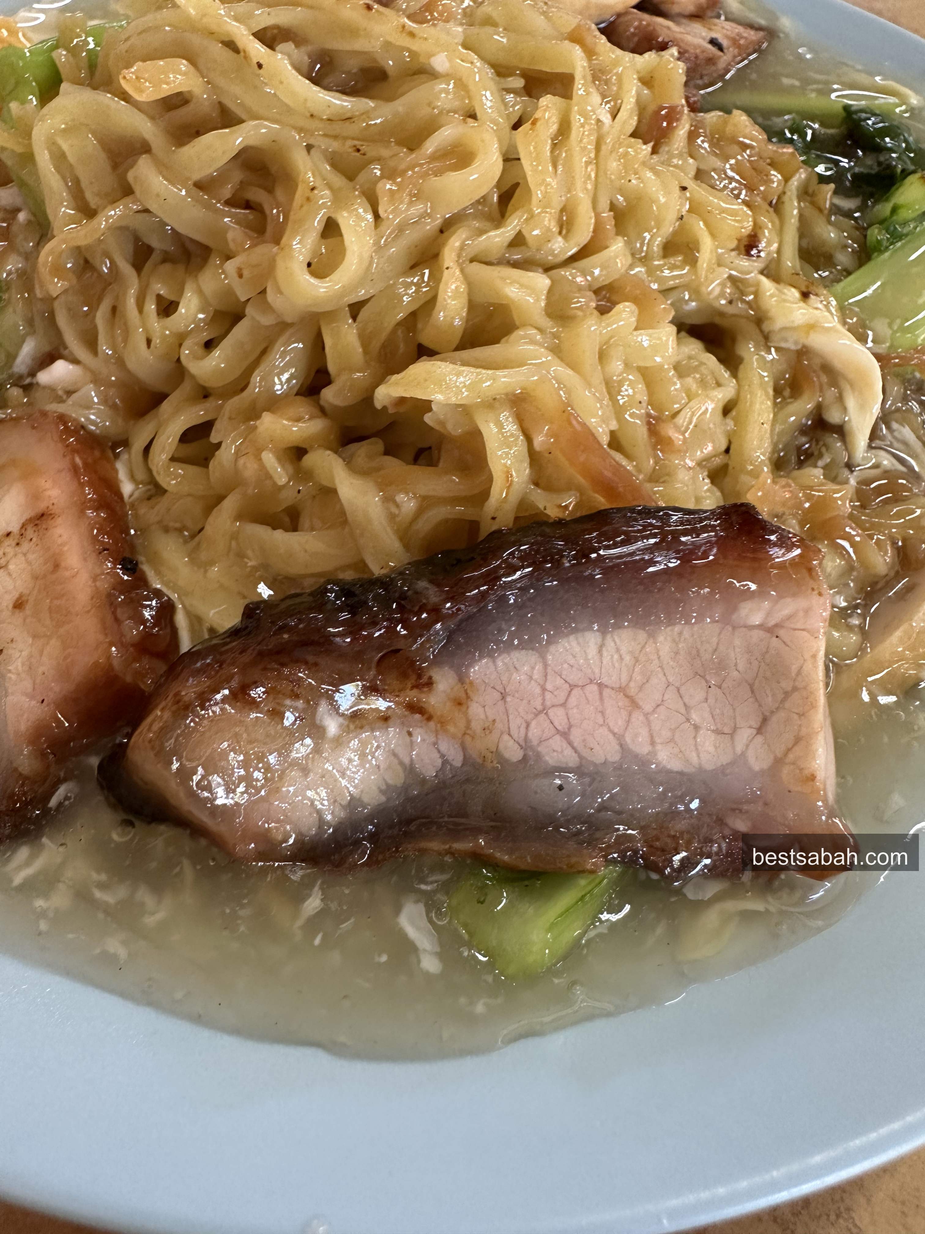 Close-up of glossy char siew and egg gravy noodles at Towering Tenom Mee Kota Kinabalu